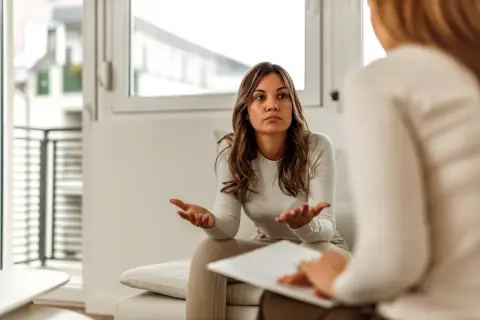 Kobieta rozmawia z psychologiem, gestykulując rękami.