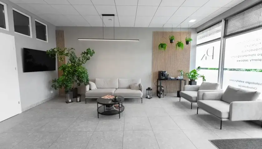 Nowoczesna poczekalnia kliniki medycznej z sofami, fotelami i roślinami.