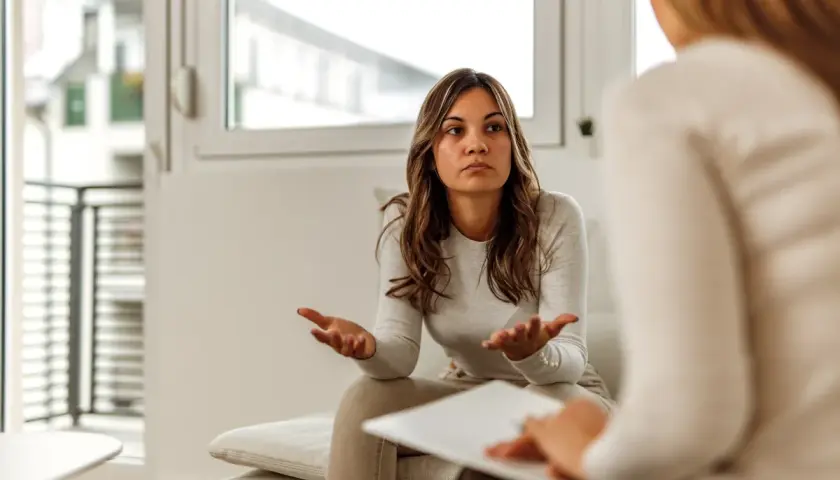 Kobieta rozmawia z psychologiem, gestykulując rękami.